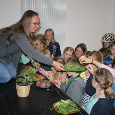 Referentin zeigt Kindern verschiedene Gemüsesorten
